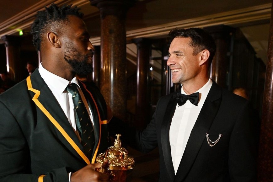 Siya Kolisi, campeón con Sudáfrica en 2019 y 2023. Dan Carter, campeón con Nueva Zelanda en 2011 y 2015. 4 copas del mundo en un foto. Crédito: World Rugby.