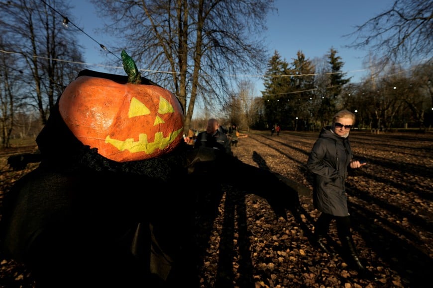 People walk past a Halloween character with pumpkin head during a Halloween festival in Kirkilai amusement park near Birzai, Lithuania October 30, 2021. REUTERS/Ints Kalnins