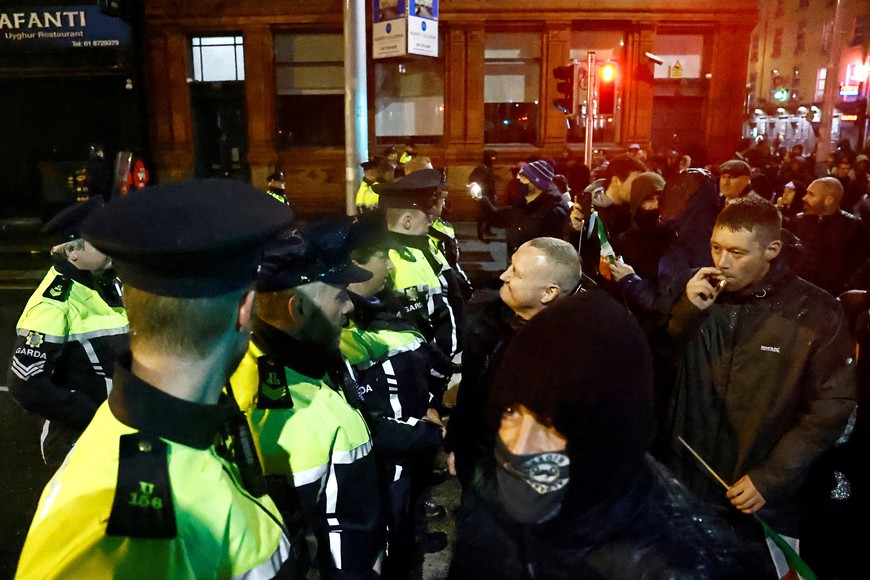 People stand in front of riot police near the scene of a suspected stabbing that left few children injured in Dublin, Ireland, November 23, 2023. REUTERS/Clodagh Kilcoyne