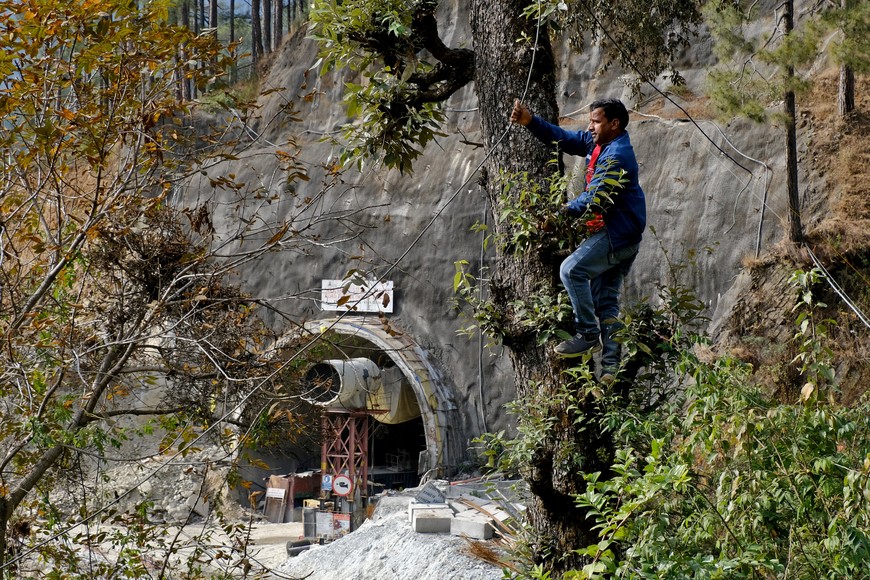 A man climbs a tree to lay a cable outside a tunnel where workers are trapped after the tunnel collapsed in Uttarkashi in the northern state of Uttarakhand, India, November 25, 2023. REUTERS/Shankar Prasad Nautiyal NO RESALES. NO ARCHIVES.
