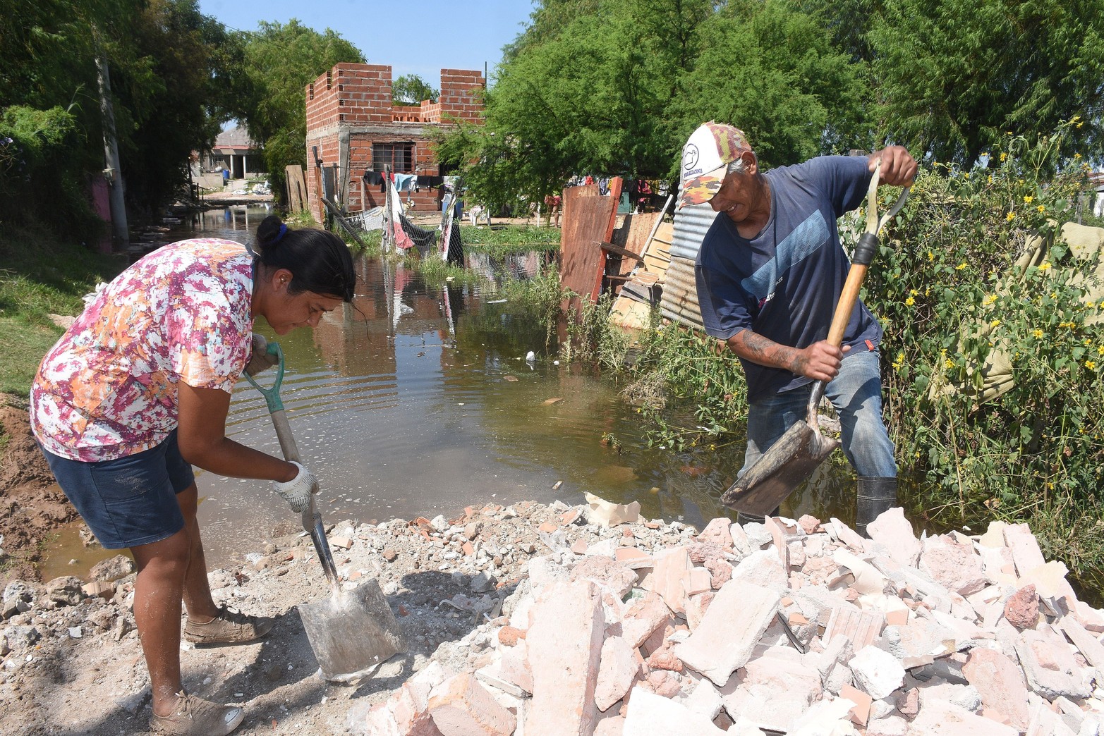 Con pala chata, dos vecinos intentan mantener el único acceso a sus viviendas. 