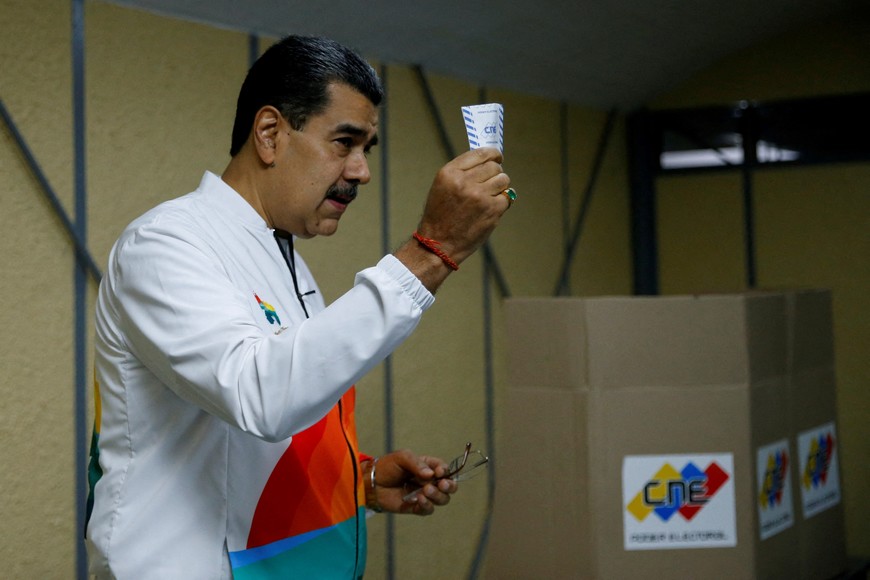 Venezuela's President Nicolas Maduro shows his ballot during an electoral referendum over Venezuela's rights to the potentially oil-rich region of Esequiba, which has long been the subject of a border dispute between Venezuela and Guyana, in Caracas, Venezuela, December 3, 2023. REUTERS/Leonardo Fernandez Viloria