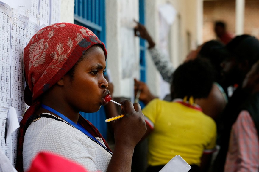 A polling agent licks a lollipop during a break at the Mavuno polling station, after working long hours during the parliamentary and presidential elections in Goma, North Kivu province of the Democratic Republic of Congo December 21, 2023. REUTERS/Thomas Mukoya