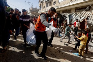 Un grupo de gazatíes arrastra un cadáver en medio de los ataques de Israel. Desde que se inició el conflicto murieron más de 20 mil palestinos. Foto: Reuters
