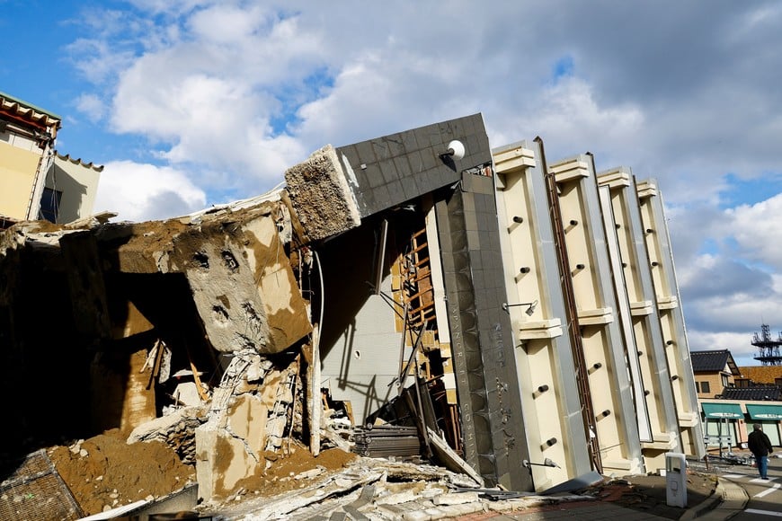 A person walks past a collapsed building, in the aftermath of an earthquake, in Wajima, Ishikawa Prefecture, Japan, January 4, 2024. REUTERS/Kim Kyung-Hoon