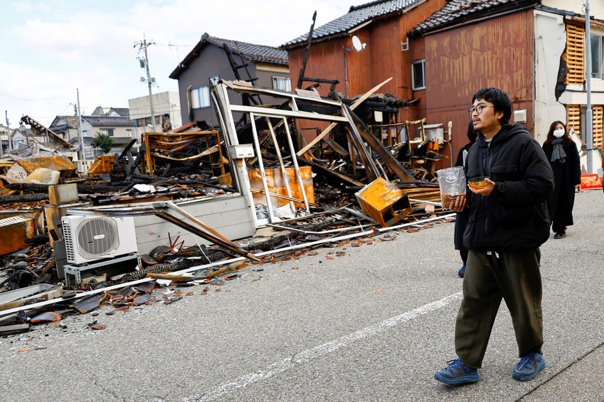 Japanese lacquer artist Kohei Kirimoto holds cat food, while searching for his cats, next to an "Asaichi" morning market which burnt down in a quake-triggered fire, in Wajima, Japan, January 4, 2024. REUTERS/Kim Kyung-Hoon