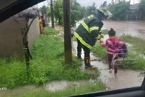 Bomberos ayudan a una familia a salir de su casa inundada.