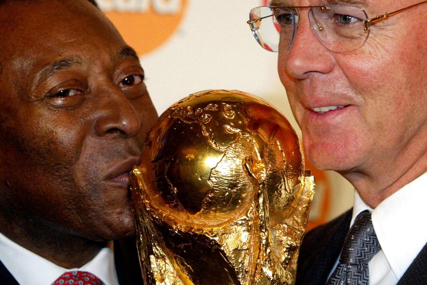 FILE PHOTO: Brazilian soccer legend Pele (L) kisses the soccer World Cup trophy as
he poses with the head of the 2006 World Cup Soccer Championship
organisation committee and former German international Franz
Beckenbauer in Berlin March 12, 2003. The two soccer stars met in
Berlin to promote Mastercard sponsorship of the 2006 World Cup.
REUTERS/Tobias Schwarz/File Photo