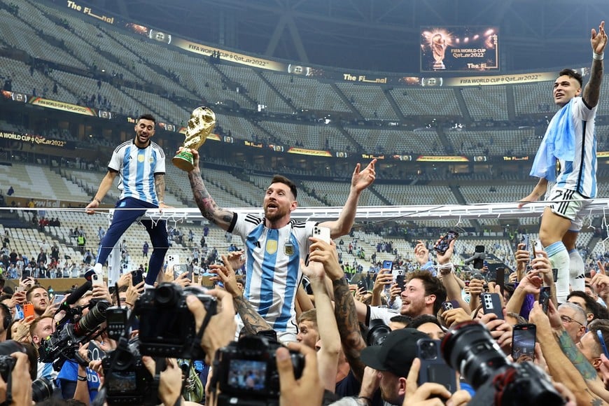 Soccer Football - FIFA World Cup Qatar 2022 - Final - Argentina v France - Lusail Stadium, Lusail, Qatar - December 18, 2022
Argentina's Lionel Messi celebrates with the trophy after winning the World Cup as Lautaro Martinez is sat atop the frame of a goal REUTERS/Kai Pfaffenbach