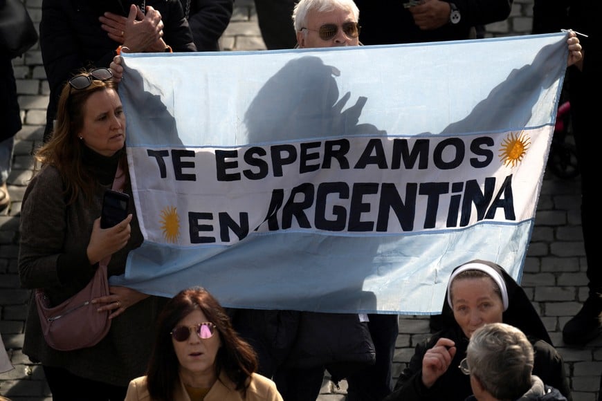 People hold cloth in the colours of the Argentine flag with a slogan as they attend the Angelus prayer led by Pope Francis at the Vatican, January 14, 2024. The slogan reads: "We are waiting for you in Argentina".  Vatican Media/­Handout via REUTERS    ATTENTION EDITORS - THIS IMAGE WAS PROVIDED BY A THIRD PARTY.