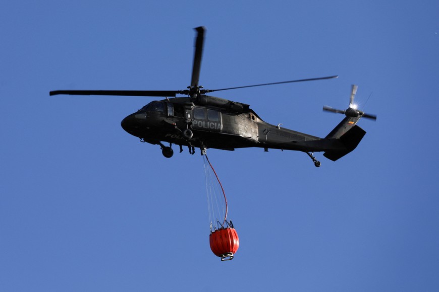 A helicopter flies with water to put out forest fires on a hill in Bogota, Colombia January 24, 2024. REUTERS/Luisa Gonzalez