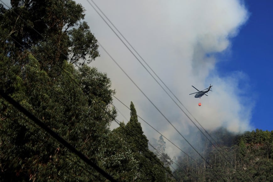 A helicopter flies with water to put out forest fires on a hill in Bogota, Colombia January 24, 2024. REUTERS/Luisa Gonzalez