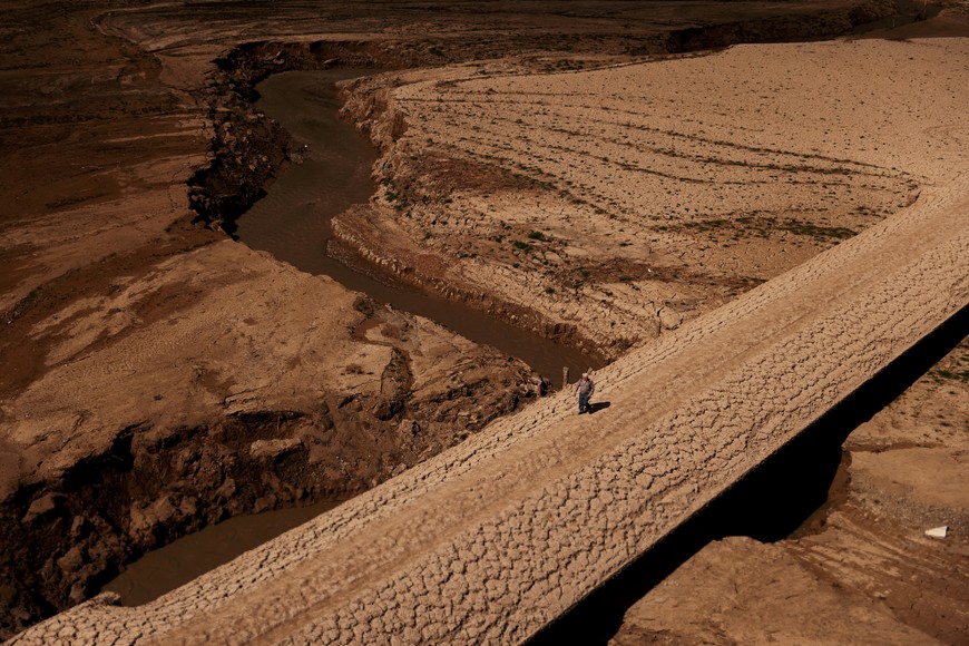 A man walks on the cracked ground of the Baells reservoir as drinking water supplies have plunged to their lowest level since 1990 due to extreme drought in Catalonia, in the village of Cersc, in the region Bergueda, Spain, March 14, 2023. REUTERS/Nacho Doce        SEARCH "GLOBAL POY 2023" FOR THIS STORY. SEARCH "REUTERS POY" FOR ALL BEST OF 2023 PACKAGES.?     TPX IMAGES OF THE DAY