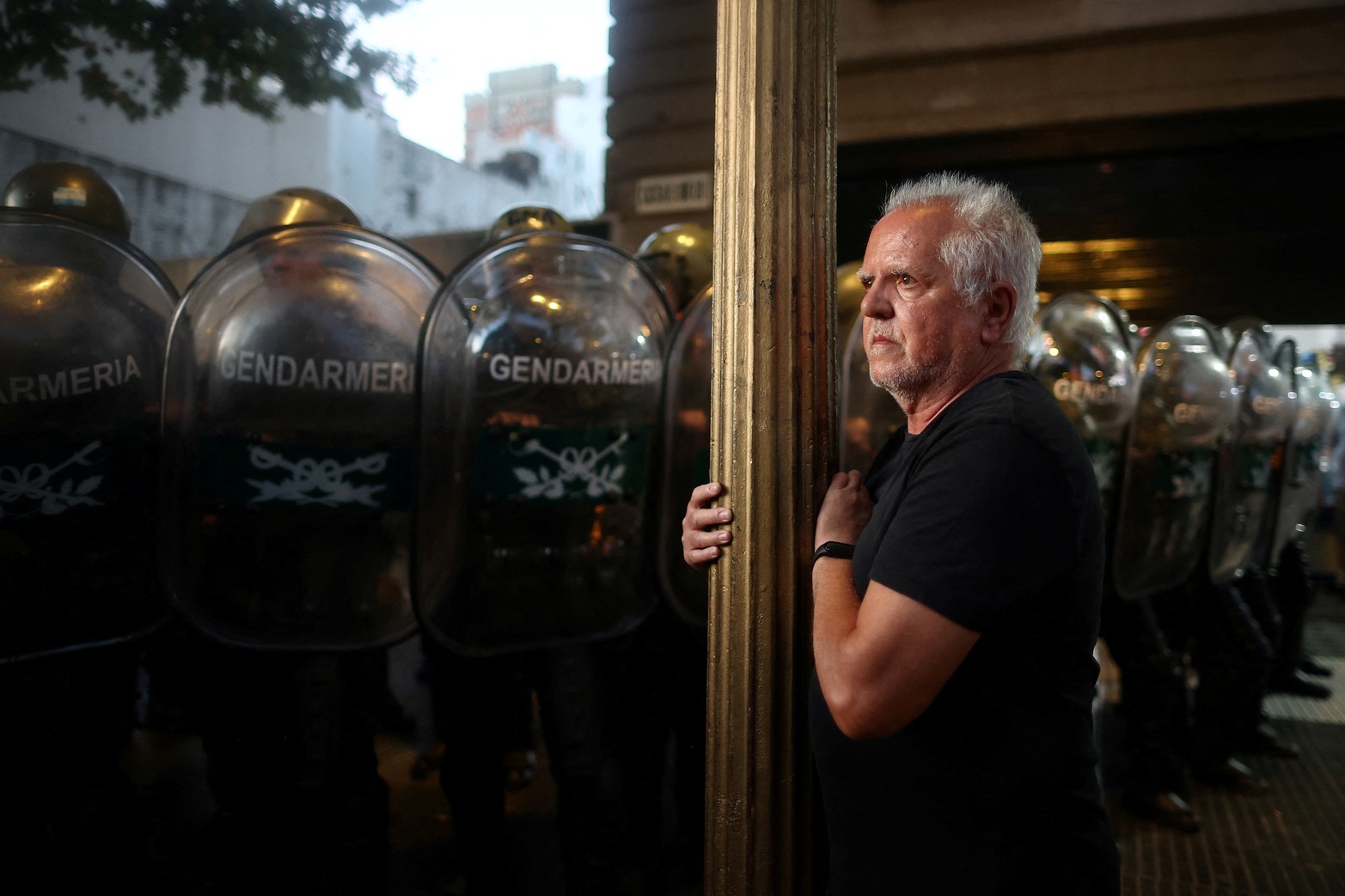 Un hombre se encuentra frente a agentes del orden mientras los manifestantes protestan el día del debate sobre el proyecto de ley de reforma económica del presidente argentino Javier Milei, conocido como el "proyecto de ley ómnibus".