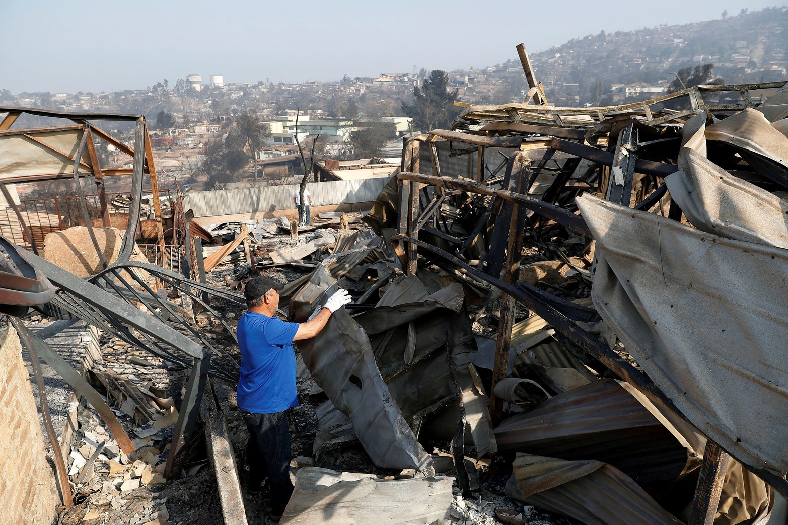 Juan Vásquez retira restos de su casa tras la propagación de incendios forestales en Viña del Mar expresa el pie de foto de la agencia internacional.