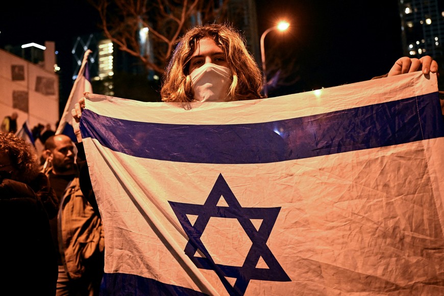 A person holds an Israeli flag during a protest against Israeli Prime Minister Benjamin Netanyahu's government, amid the ongoing conflict between Israel and the Palestinian Islamist group Hamas, in Tel Aviv, Israel, February 17, 2024. REUTERS/Dylan Martinez