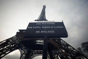 A sign reading "Due to a strike, the Eiffel Tower is closed. We apoligize" hangs in front of the Eiffel Tower in Paris, France, February 19, 2024. Picture taken through glass. REUTERS/Sarah Meyssonnier