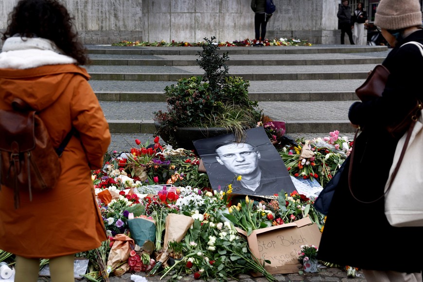 Women look at flowers and pictures at the National Monument on Dam Square in Amsterdam after the funeral of Russian opposition politician Alexei Navalny, in Amsterdam, Netherlands, March 1, 2024. REUTERS/Piroschka van de Wouw