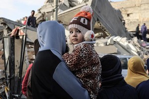 Palestinos delante de los escombros de un edificio bombardeado por fuerzas israelíes en Rafah, al sur de Gaza.