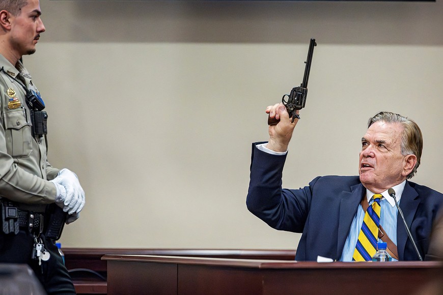 As Santa Fe County Deputy Levi Abeyta (left) watches, Expert witness for the defense Frank Koucky III demonstrates how to uncock a gun like the one used in the Rust shooting during testimony in  Hannah Gutierrez-Reed’s  involuntary manslaughter trial at the First Judicial District Courthouse in Santa Fe on Tuesday, March 5, 2024.    Jim Weber/The New Mexican/Pool via REUTERS