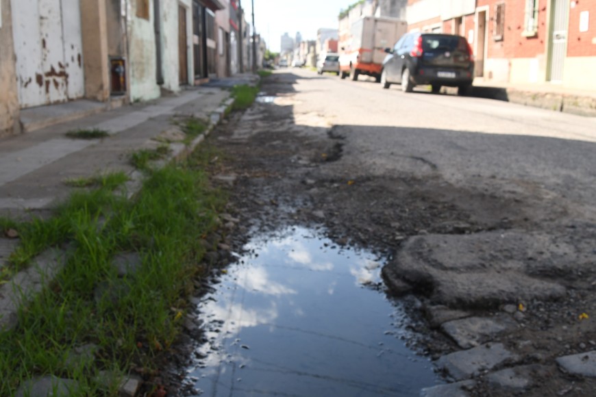 Un peligro. La calzada de pasaje Magallanes al 4100 presenta pozos profundos -tapados por agua de lluvia- y también "bodoques" de pavimento. Días atrás, una motociclista se cayó. Foto: Flavio Raina.