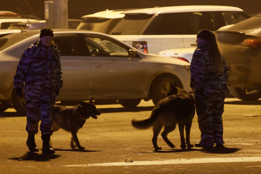 Russian law enforcement officers with dogs patrol a parking area near the Crocus City Hall concert venue following a shooting incident, outside Moscow, Russia, March 23, 2024. REUTERS/Maxim Shemetov