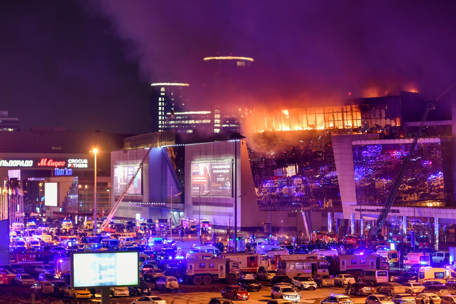 Humo del fuego se eleva sobre la incendiada sala de conciertos Crocus después de un incidente de tiroteo. Cientos de ambulancias aguardan para rescatar heridos, en el noroeste de Moscú, Rusia. 