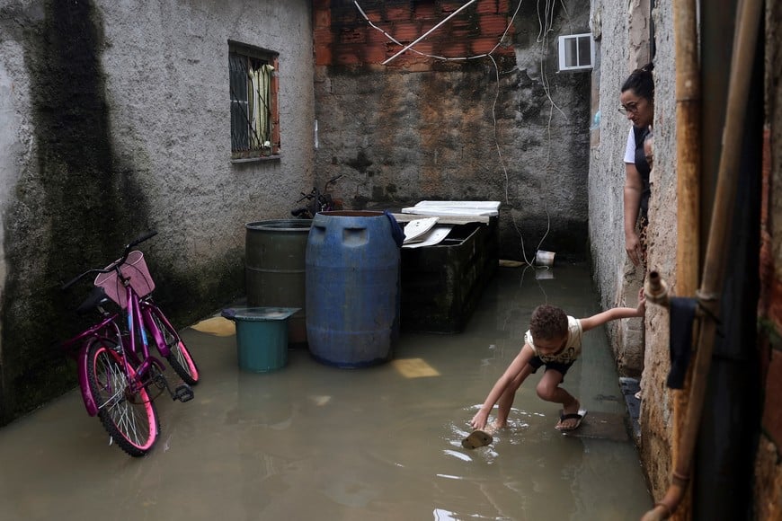 A child catches a flip flop outside a house surrounded by flood waters after heavy rains in Duque de Caxias, Rio de Janeiro state, Brazil, March 24, 2024. REUTERS/Pilar Olivares