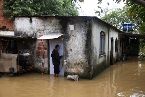 Construction worker Nicelio Goncalves, 52, opens the door oh his flooded house after heavy rains in Duque de Caxias, Rio de Janeiro state, Brazil, March 24, 2024. REUTERS/Pilar Olivares