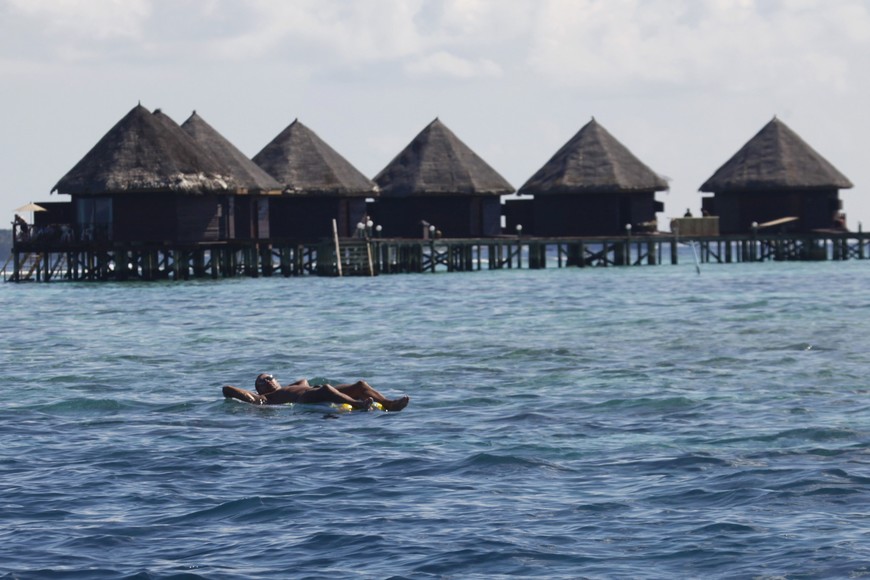 A tourist floats in front of huts at a resort island at the Male Atoll December 8, 2009. The largest-ever climate talks formally opened on Monday in Denmark aiming to agree the outlines of global deal to stave off dangerous climate change, such as rising seas and more intense storms. REUTERS/Reinhard Krause (MALDIVES POLITICS ENVIRONMENT TRAVEL) islas maldivas atolon male  islas maldivas atolon male hoteles