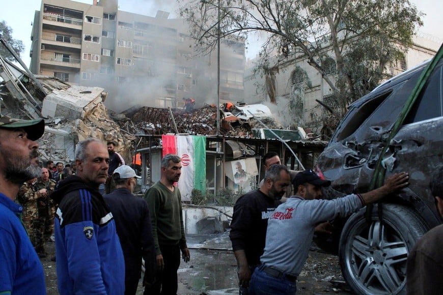 People gather near a damaged site, hauling a destroyed vehicle away, after what Syrian and Iranian media described as an Israeli air strike on Iran's consulate in the Syrian capital Damascus April 1, 2024. REUTERS/Firas Makdesi 
     TPX IMAGES OF THE DAY