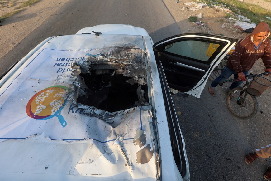A Palestinian man rides a bicycle past a damaged vehicle where employees from the World Central Kitchen (WCK), including foreigners, were killed in an Israeli airstrike, according to the NGO as the Israeli military said it was conducting a thorough review at the highest levels to understand the circumstances of this "tragic" incident, amid the ongoing conflict between Israel and Hamas, in Deir Al-Balah, in the central Gaza, Strip April 2, 2024. REUTERS/Ahmed Zakot     TPX IMAGES OF THE DAY