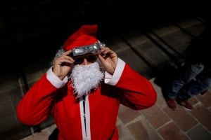 A man dressed as Santa Claus uses special protective glasses to observe the solar eclipse over South America, visible in parts of Chile and Argentina, in Bariloche, Patagonia, Argentina, December 14, 2020. REUTERS/Carlos Barria