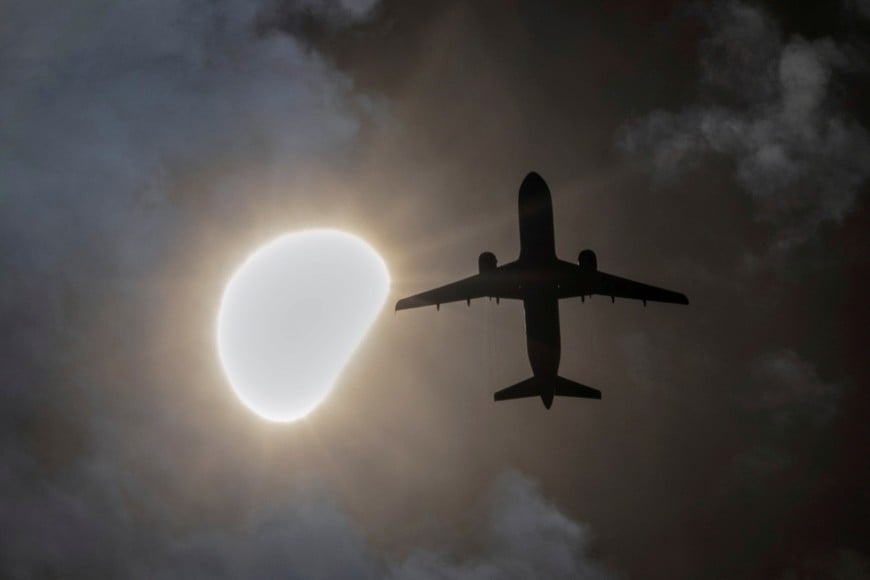 An airplane passes during a partial solar eclipse seen from Queens, New York City, U.S., April 8, 2024. REUTERS/Andrew Kelly     TPX IMAGES OF THE DAY