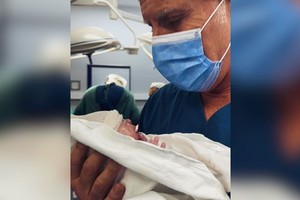 Fantino sosteniendo a su hijo en brazos y mirando al bebe obnubilado.