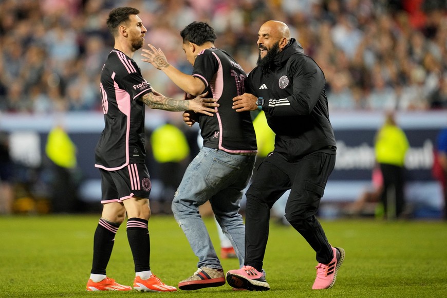 Apr 13, 2024; Kansas City, Kansas, USA; Inter Miami CF forward Lionel Messi (10) and security talk to a fan on the pitch during the second half against Sporting Kansas City at GEHA Field at Arrowhead Stadium. Mandatory Credit: Jay Biggerstaff-USA TODAY Sports