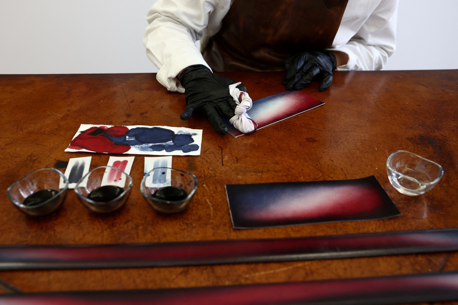 Un empleado trabaja en las pátinas de las partes de cuero de los trajes que usarán los atletas del equipo francés para la ceremonia de apertura de la exclusiva marca de ropa masculina de LVMH, Berluti, en una sala de exposición en la sede de Berluti en París, Francia, el 10 de abril de 2024. 