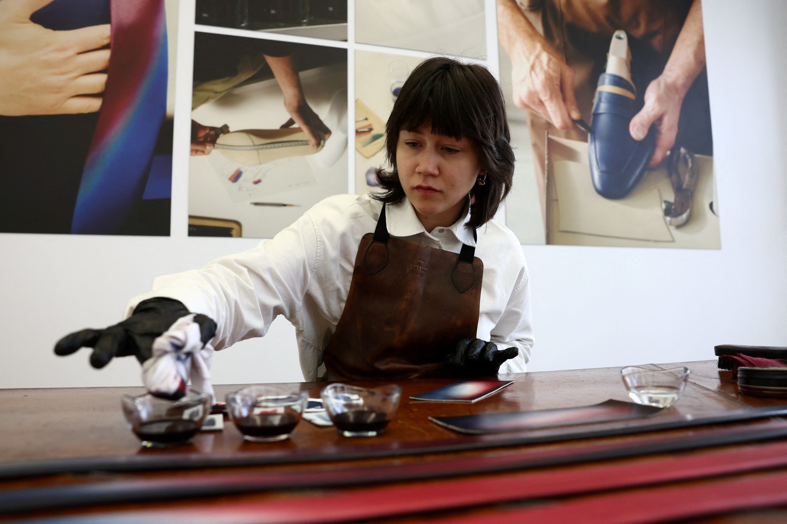 Un empleado trabaja en las pátinas de las partes de cuero de los trajes que usarán los atletas del equipo francés para la ceremonia de apertura de la exclusiva marca de ropa masculina de LVMH, Berluti, en una sala de exposición en la sede de Berluti en París, Francia.
