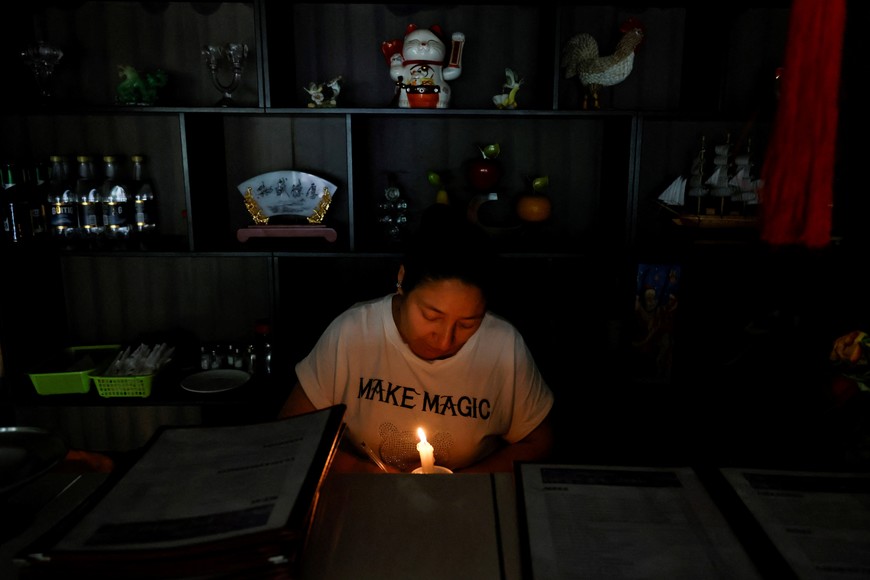 A saleswoman waits for customers at her restaurant during a planned power cut after Ecuador's President Daniel Noboa declared an energy emergency due to a drought affecting hydro-electricity production, in Quito, Ecuador April 18, 2024. REUTERS/Karen Toro