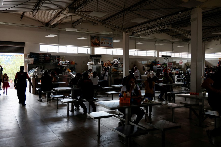 Customers eat in a darkened market square during a planned power cut after Ecuador's President Daniel Noboa declared an energy emergency due to a drought affecting hydro-electricity production, in Quito, Ecuador April 18, 2024. REUTERS/Karen Toro
