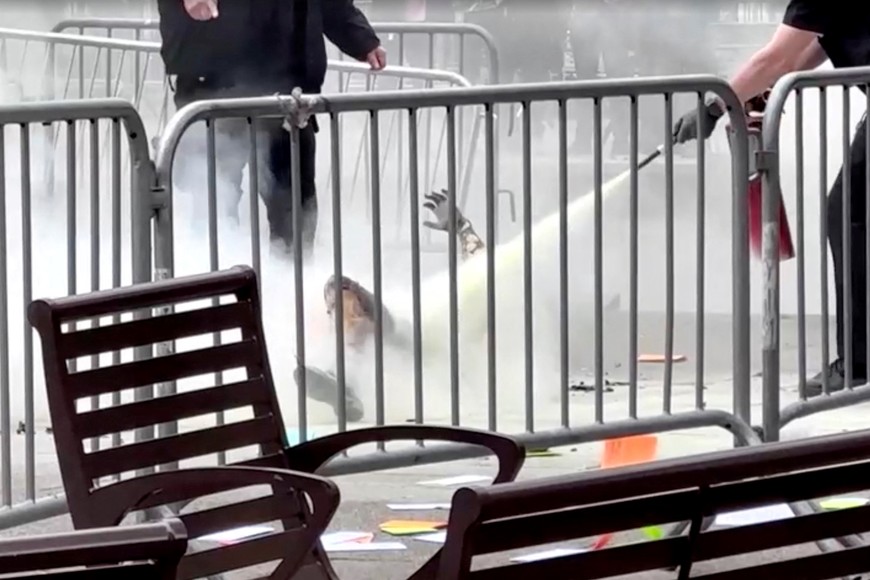 SENSITIVE MATERIAL. THIS IMAGE MAY OFFEND OR DISTURB   A police officer uses a fire extinguisher on a person who set himself on fire outside the courthouse where former U.S. President Donald Trump's criminal hush money trial is underway, in New York, U.S., April 19, 2024, in this screen grab taken from a video. Reuters TV via REUTERS