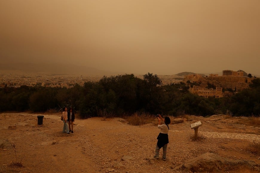 Tourists visit the Filipappou hill with the views of the Acropolis, as African dust from the desert of Sahara covers the city of Athens, Greece, April 23, 2024. REUTERS/Louisa Gouliamaki