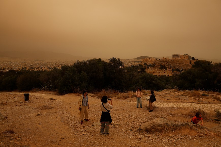 Tourists visit the Filipappou hill with the views of the Acropolis, as African dust from the desert of Sahara covers the city of Athens, Greece, April 23, 2024. REUTERS/Louisa Gouliamaki
