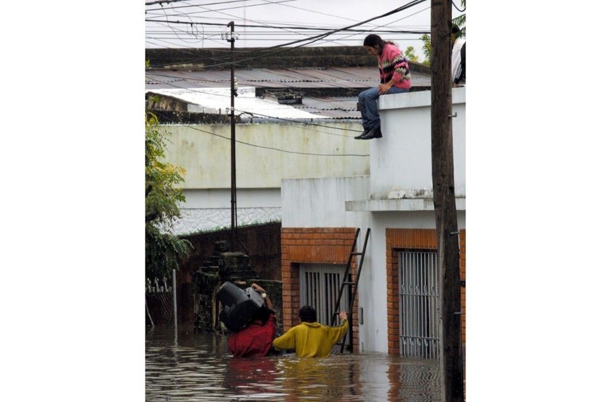 Televisor. Vecinos inundados tratan de salvar un televisor subiéndolo al techo de una vivienda.