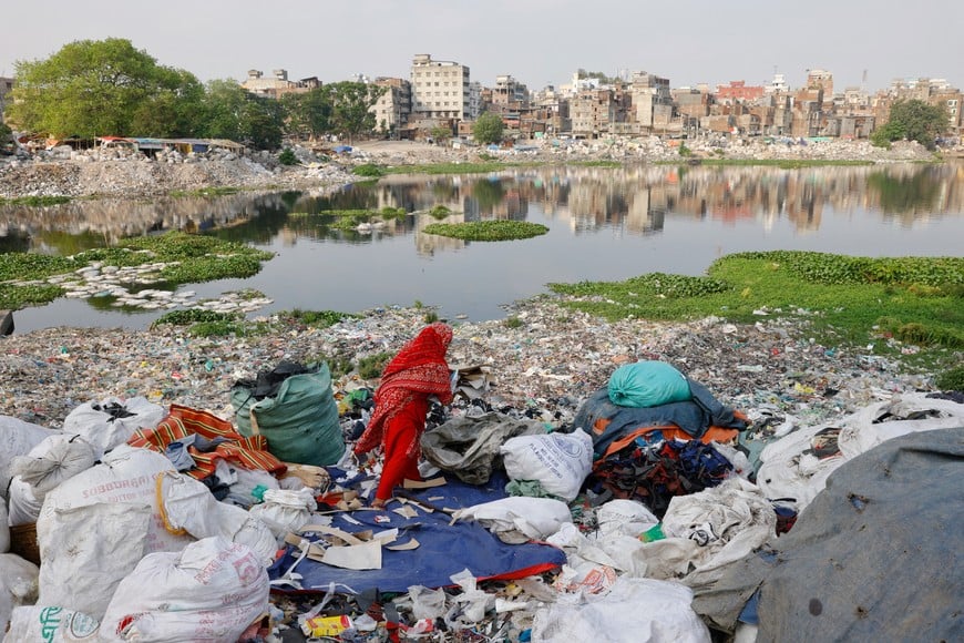 Plastic waste floats in the Buriganga river while a woman sorts it for recycling in Dhaka, Bangladesh, April 21, 2024. REUTERS/Mohammad Ponir Hossain