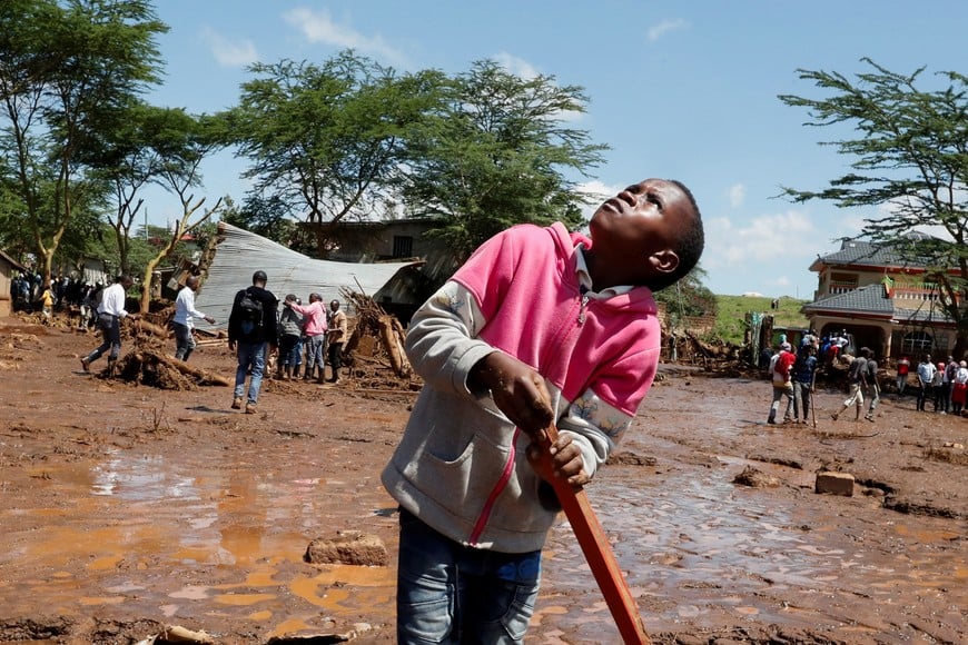A boy looks at a helicopter hovering near the search and rescue location after heavy flash floods wiped out several homes when a dam burst, following heavy rains in Kamuchiri village of Mai Mahiu, Nakuru County, Kenya April 29, 2024. REUTERS/Thomas Mukoya