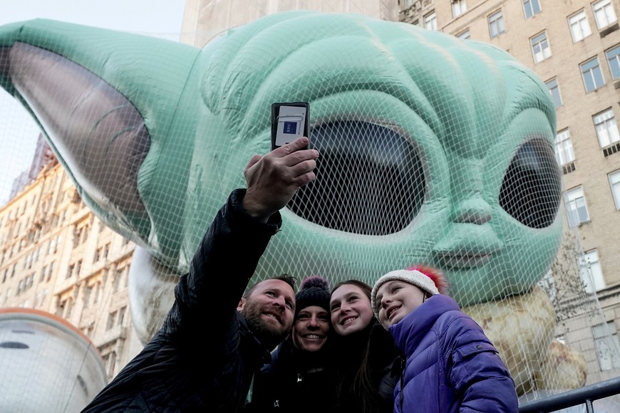 People take a selfie in front of the Grogu "Baby Yoda" balloon as it is inflated the day before the Macy's Thanksgiving Day Parade in the Manhattan borough of New York City, New York, U.S., November 24, 2021.  REUTERS/Carlo Allegri     TPX IMAGES OF THE DAY