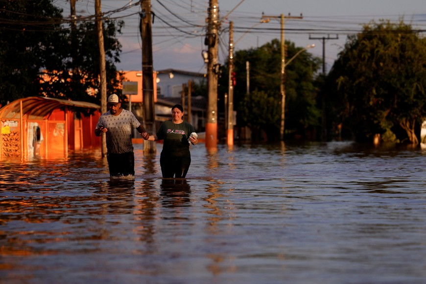 People walk through flood waters in Canoas, at the Rio Grande do Sul state, Brazil, May 5, 2024. REUTERS/Amanda Perobelli
