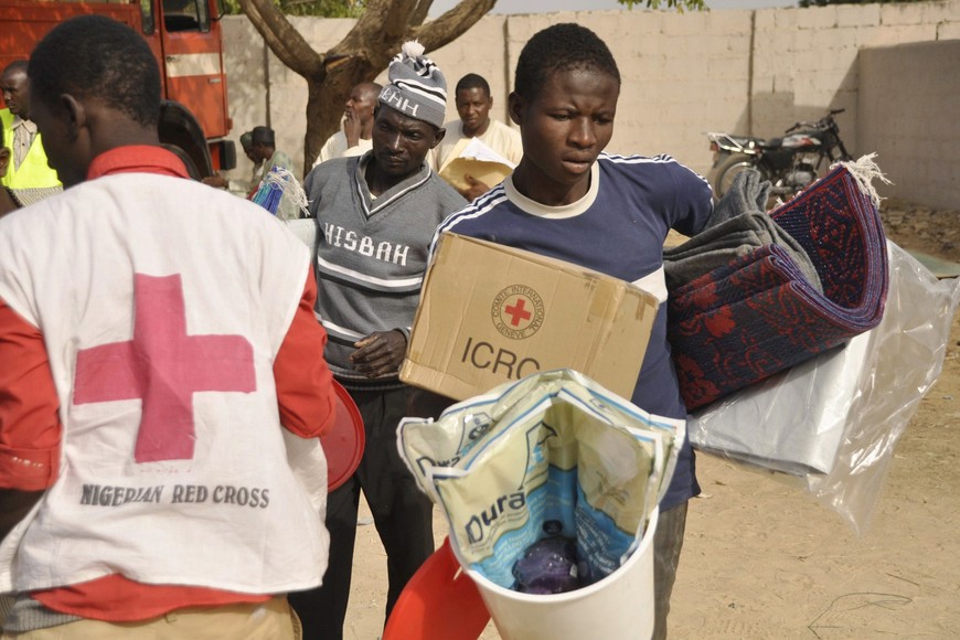 A man carries relief materials distributed by the Red Cross in Kano at a relief camp for people fleeing the Boko Haram violence, in Dawaki, a local government area in Kano, December 16, 2014. REUTERS/Stringer (NIGERIA - Tags: CIVIL UNREST SOCIETY) nigeria kano nigeria desplazados por la violencia religiosa de boko haram cruz roja reparte alimentos y medicamentos en campo de Dawaki
