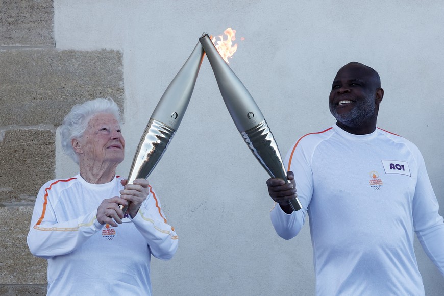 Colette Cataldo receives the Olympics torch from French former football player Basile Boli during the relay ahead Paris 2024 Olympic games in Marseille, France, May 9, 2024. REUTERS/Benoit Tessier